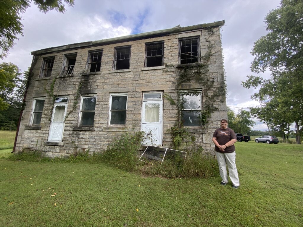 Vicky Garner stands next the the house in Graham Township, Jefferson County, Ind., that was built around 1818 by her fifth-great-grandfather, Abraham Walton, in September 2022.